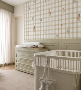 Quarto de bebê em tons neutros com berço branco, cômoda verde clara e papel de parede infantil fazendinha com padrão xadrez bege e ilustrações minimalistas de animais.